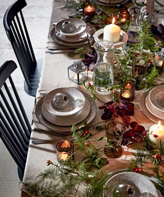 Christmas dining table decorated with colorful foliage, tableware, decorations and candles