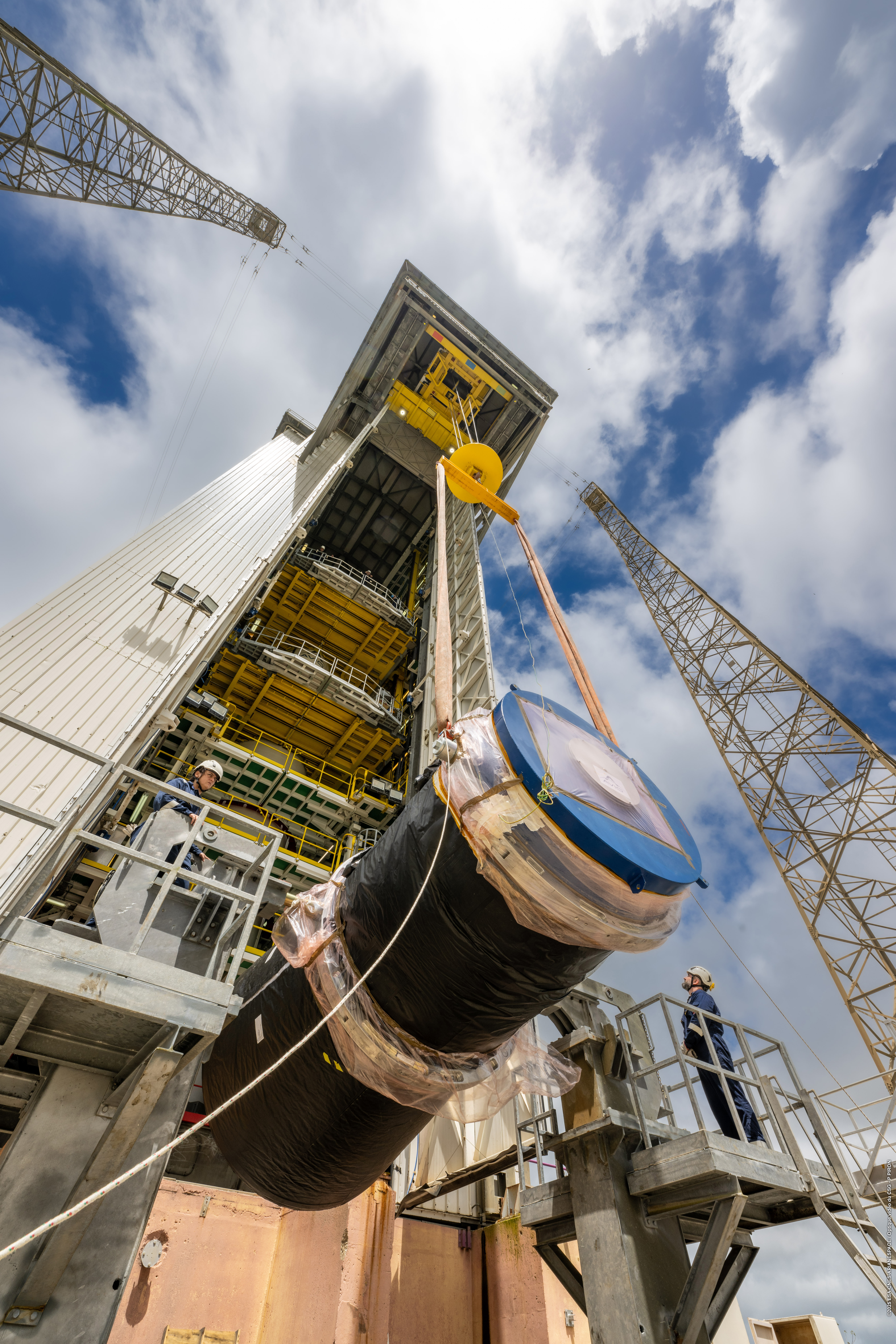 A large black cylinder is raised on a crane.