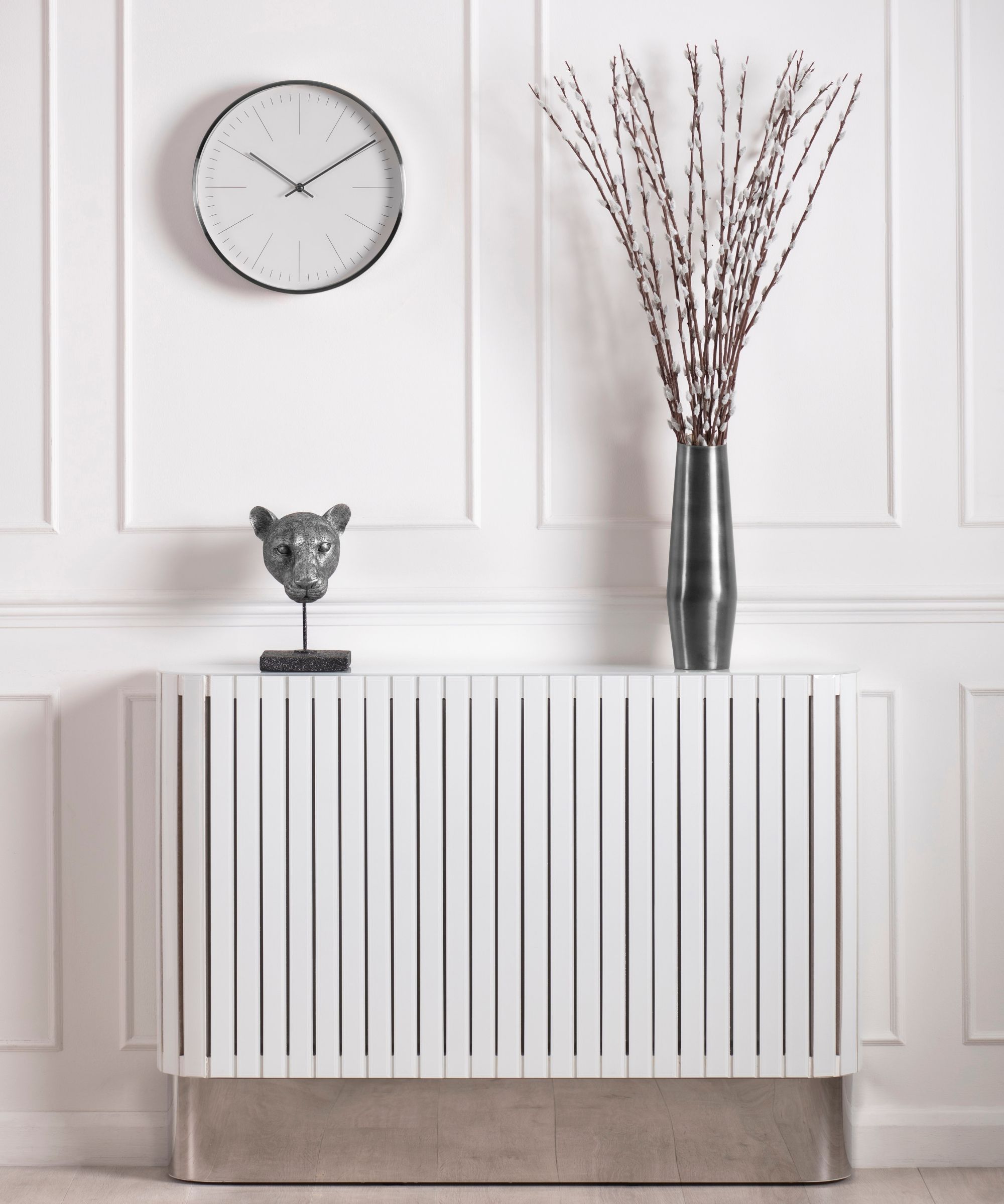 A sleek white slatted radiator cover doubles as a console, styled with a sculptural vase and modern artwork for a minimalist hallway look.