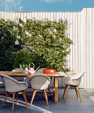 An example of garden shade ideas showing an outdoor dining area next to a living wall