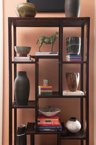 shelving with art and books in front of orange wall