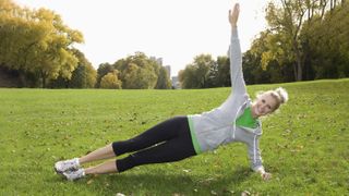 Woman performing side plank exercise in park