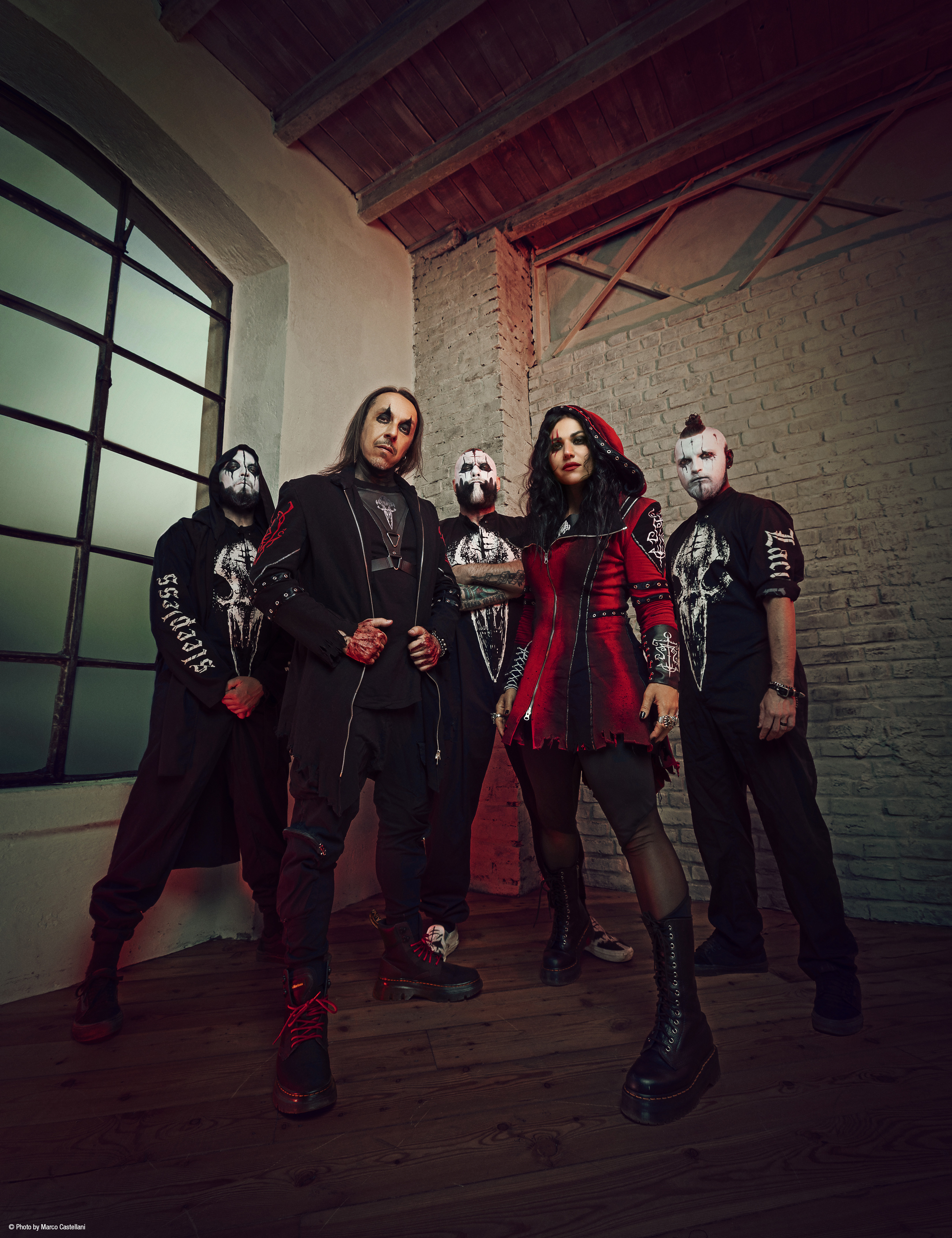 Lacuna Coil posing in heavy makeup and facepaint in front of a brick wall
