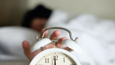 Cropped Hand Of Person Turning Off Alarm Clock - stock photo