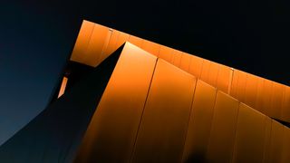 An ethereal abstract image shot at the golden hour of the metal facade architecture of a modern building. There are lines and angles moving through this high-contrast image. The image features a close up of an office building in Miamisburg Ohio