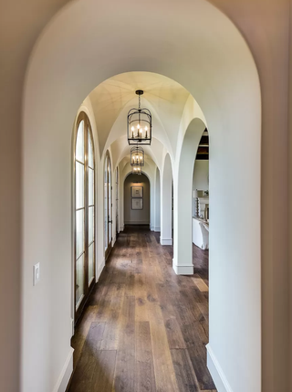 hallway with off-white walls, and dark floors, vaulted ceilings