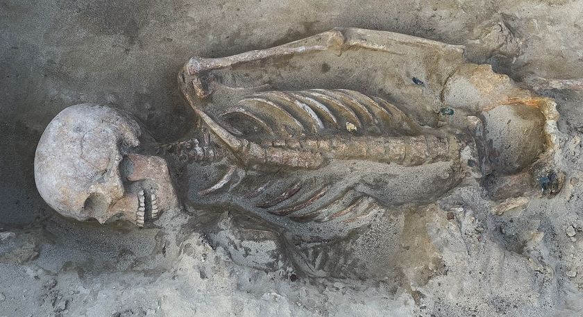 A skeleton of a man lying in the dirt