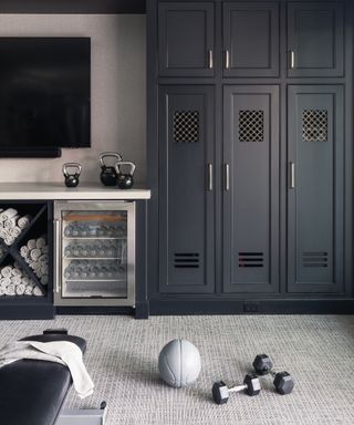 Gym with carpeted floor, bench, ball, and weights, built-in storage, drinks refrigerator and rolled towels