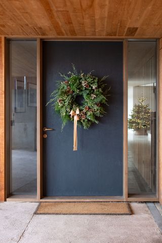 natural Christmas wreath on grey door with champagne ribbon