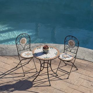 tiled effect bistro dining set on a patio by a pool