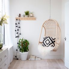 White bedroom with hanging chair and plants