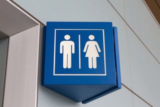 A sign outside a bathroom contains both the symbol for males and the symbol for females.