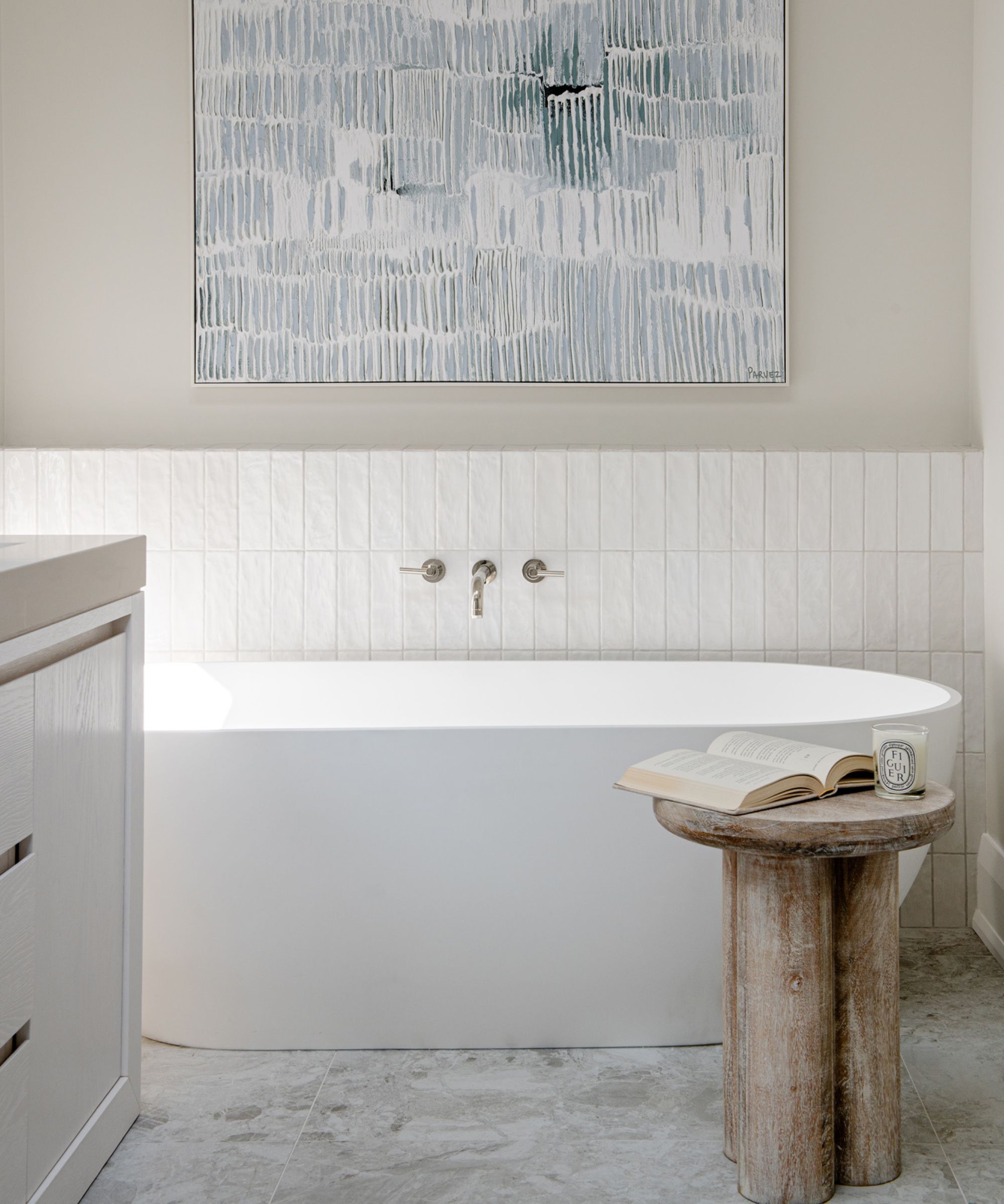 A bathroom with a freestanding tub and a large piece of artwork hanging above