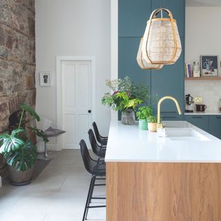 Kitchen with white flooring and wall, blue kitchen cabinets, and a kitchen island with white worktop and wooden sides