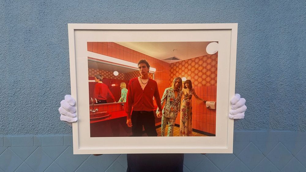 A man holds a framed photo that was banned from a photograph competition for looking like AI art frmo 