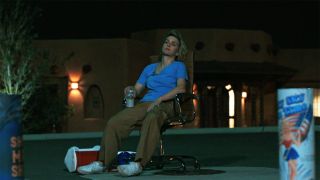 A seated Carol looking at some fireworks at night in Pluribus episode 7
