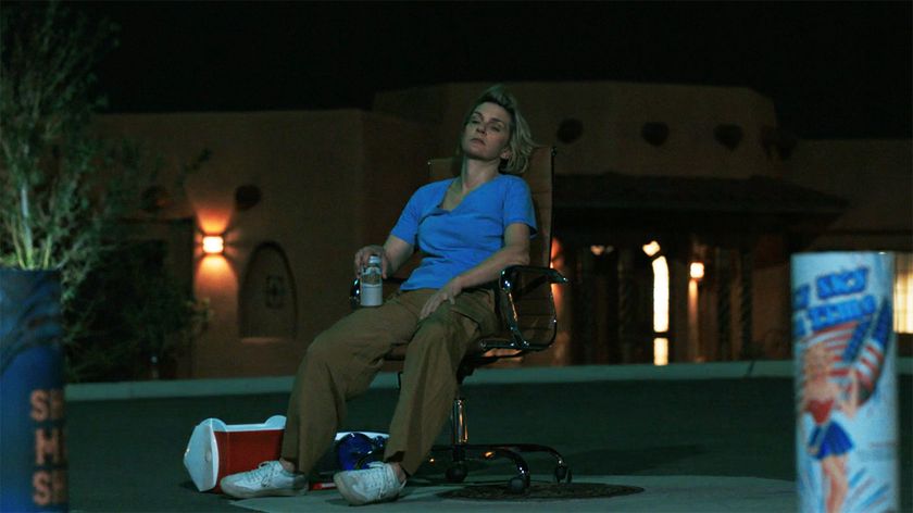 A seated Carol looking at some fireworks at night in Pluribus episode 7