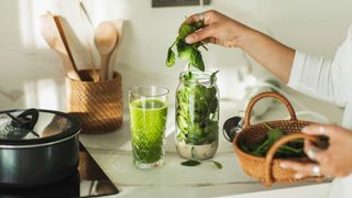 Woman blending up spinach and milk in a blender to create a smoothie rich in vitamin D