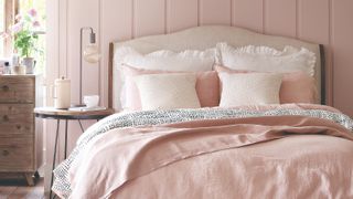 Pink bedroom with a bed with statement headboard and a bedside table