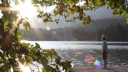 A man stands on a dock with sun shining