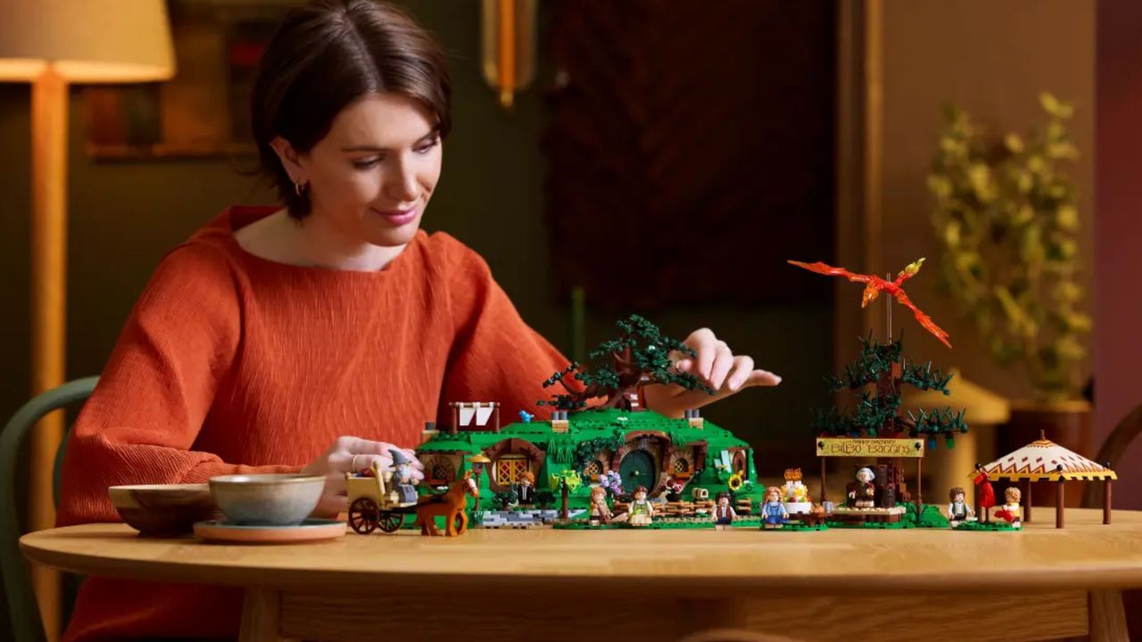 A woman building Lego The Shire set on a wooden table