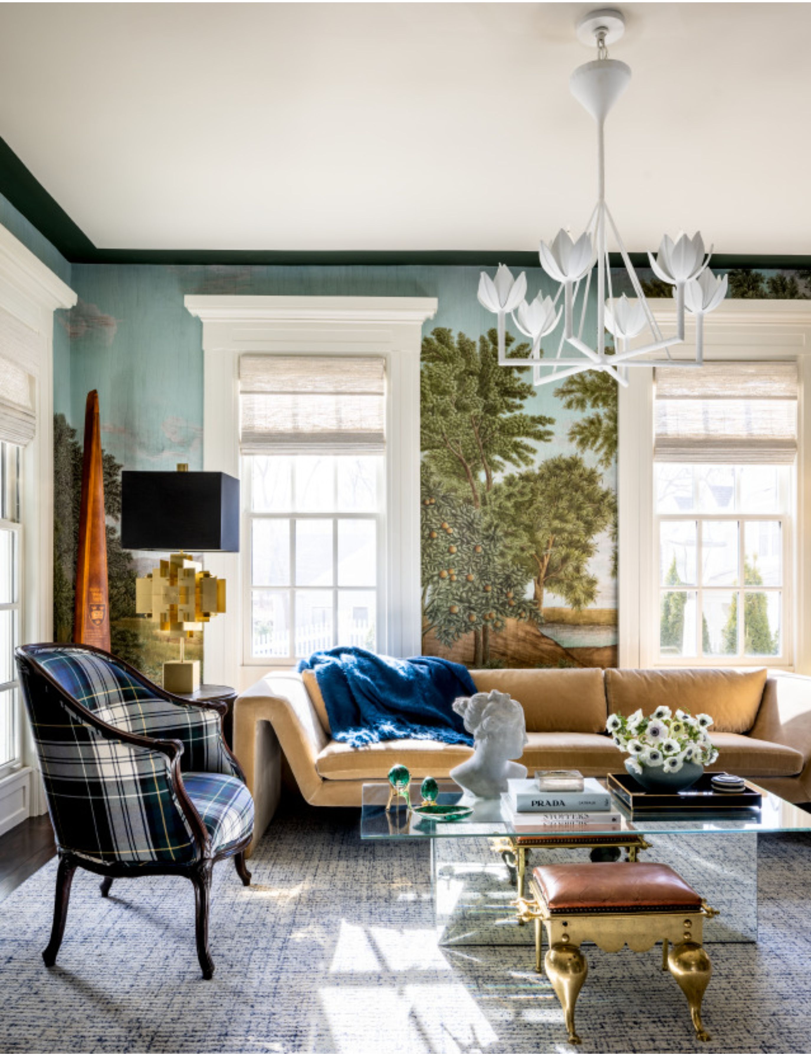 Bright living room featuring a botanical wallpaper mural, a tartan accent chair, angular velvet sofa, and antique accents