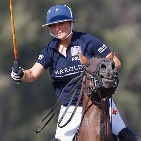 Zara Tindall riding a polo horse carrying a mallet and wearing a blue jersey and helmet