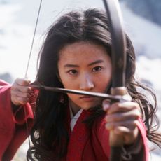 Female archer draws back her bow.