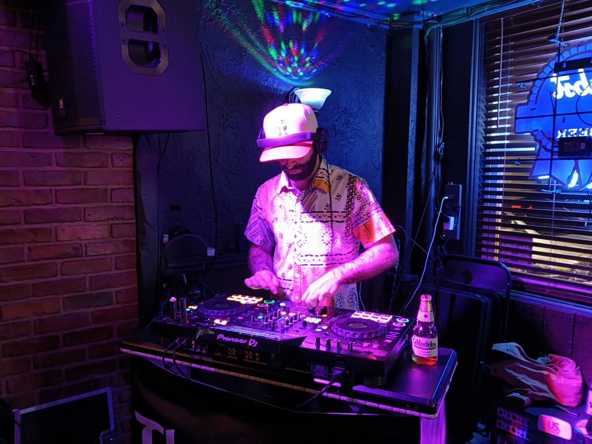 A man in a dimly lit room on a DJ turntable