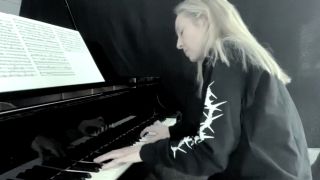 A blonde woman in a black, long-sleeve shirt playing piano