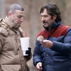 tim robinson wears a brown coat and holds a big gulp cup while looking at a mushroom with paul rudd in a blue and red coat in the movie friendship