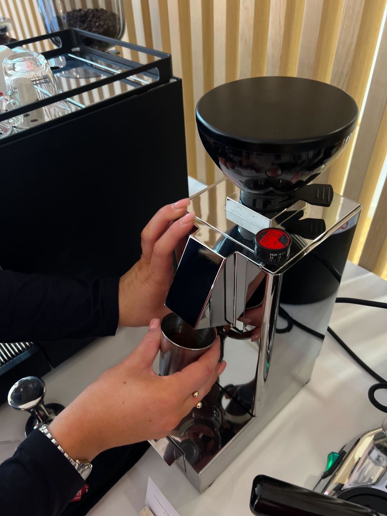Image of two hands grinding coffee from a silver coffee grinder.