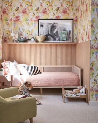 girls bedroom with shiplap walls, shelf, wallpaper, wooden bed with pink quilt, green armchair
