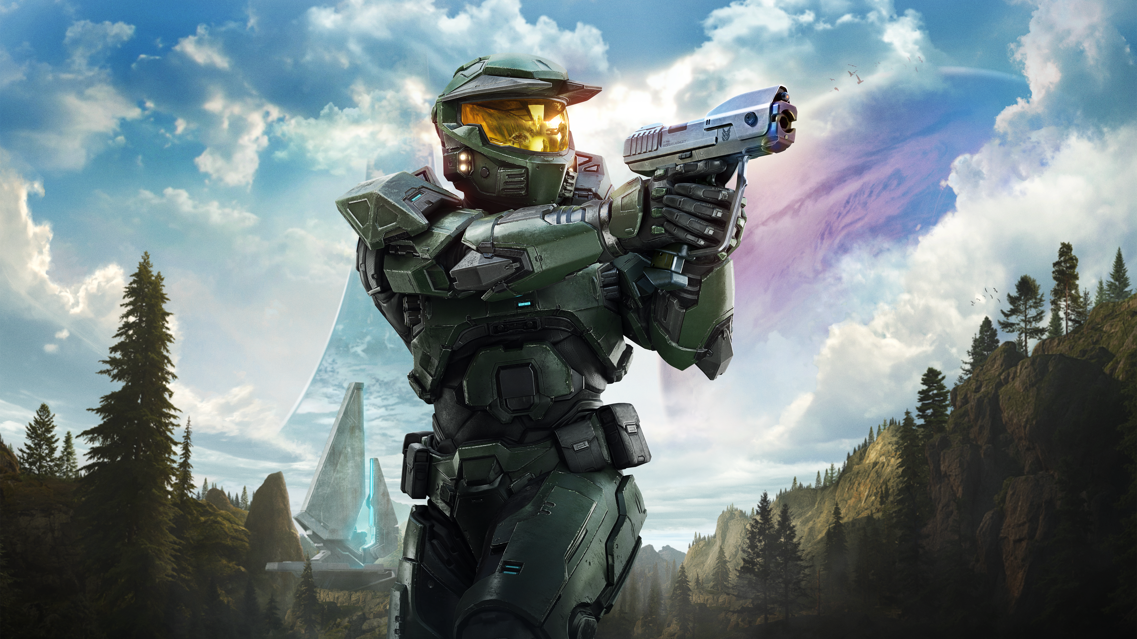 Master Chief aims a sidearm in Halo: Campaign Evolved, standing before towering Forerunner structures and a ringworld landscape beneath a dramatic alien sky