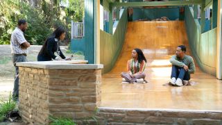 Morton and Ava looking at Janine and Gregory who are sitting on a slide.