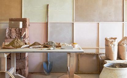 expert guide to plaster in old homes: room with exposed walls and bags of plaster