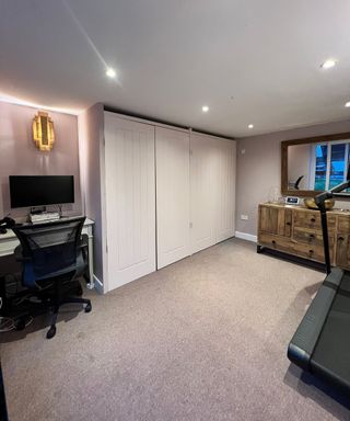 A garden outbuilding home office with desk, chair, carpeted floor and wall lighting fixture