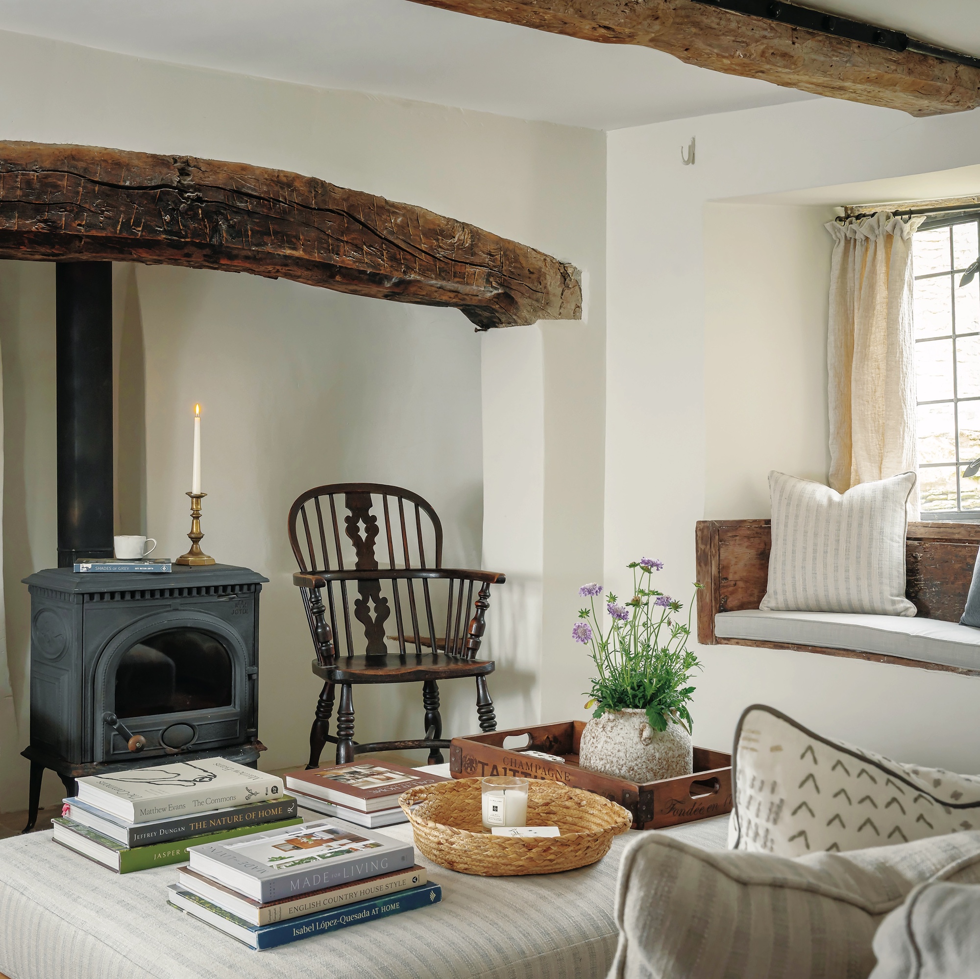 cottage sitting room with wood burner stove in inglenook fireplace and window seat