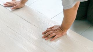 person installing vinyl flooring over tiles