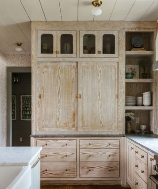 unpainted wooden kitchen pantry with brass hardware and sliding doors