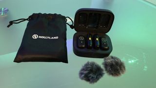 Shot of the complete kit, including the charging case holding the mics and receiver, plus a draw-string bag which holds the entire kit and accessories such as windshields