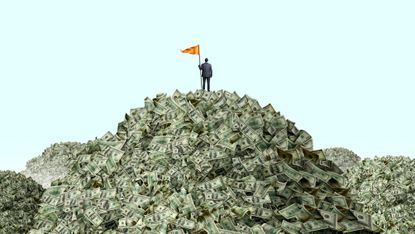 A man plants an orange flag on top of a huge pile of cash.
