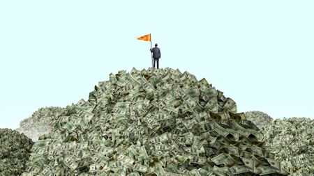 A man plants an orange flag on top of a huge pile of cash.