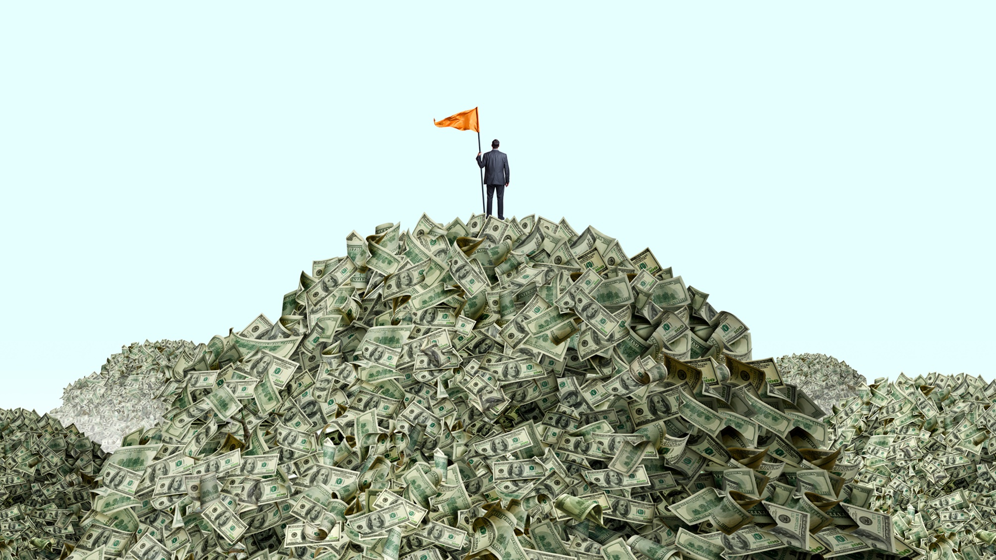A man plants an orange flag on top of a huge pile of cash.