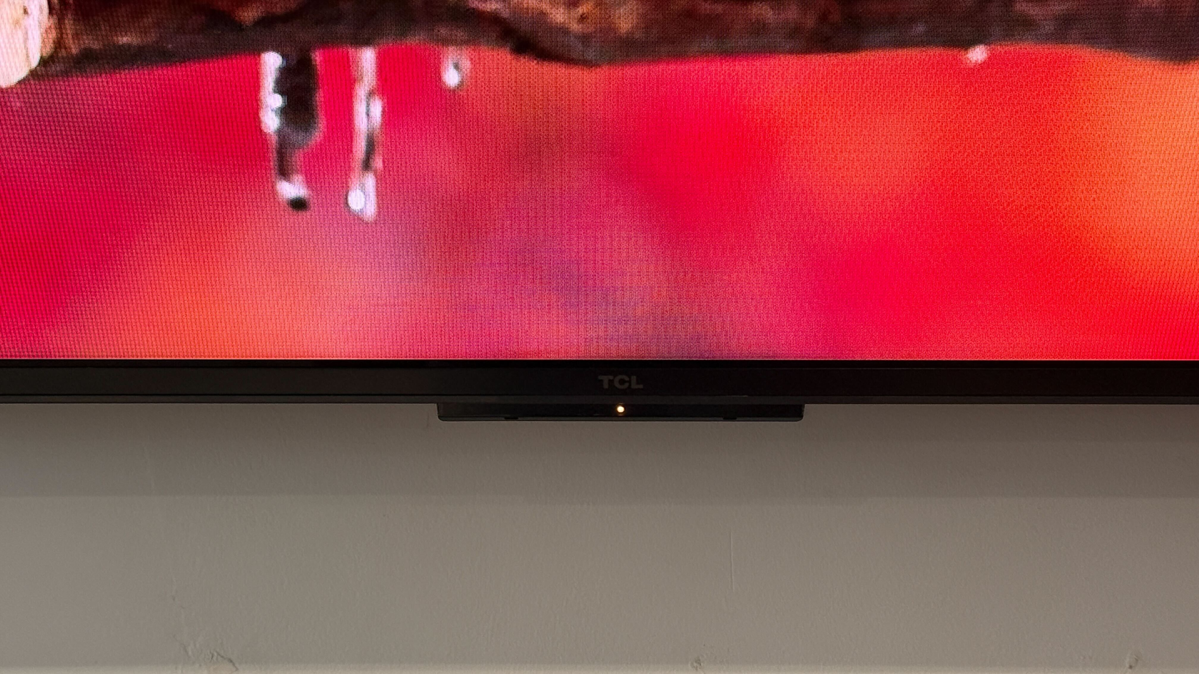 Wall-mounted TCL C7L with vibrant demo content on screen