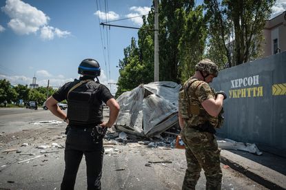 Ukrainian soldiers stand by the remains of a Russian artillery attack. 