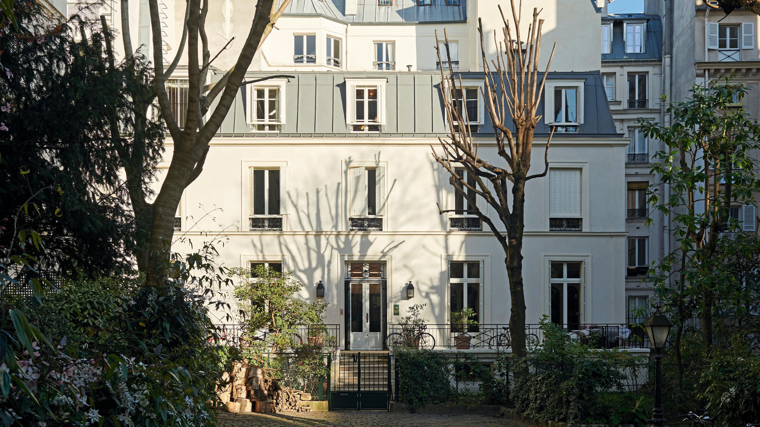 the exterior of a large Parisian apartment with a garden full of trees