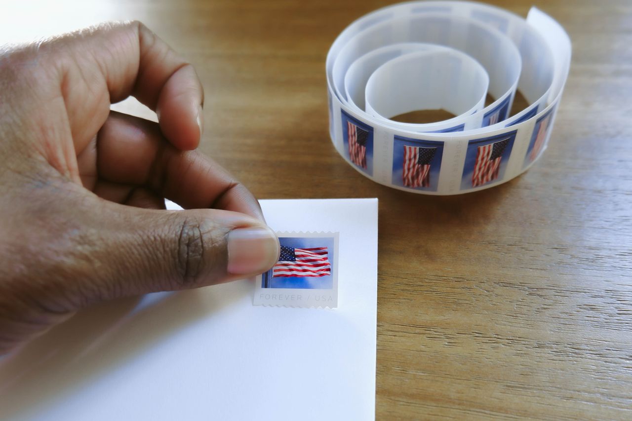 Woman Places Postage Stamp on Envelope