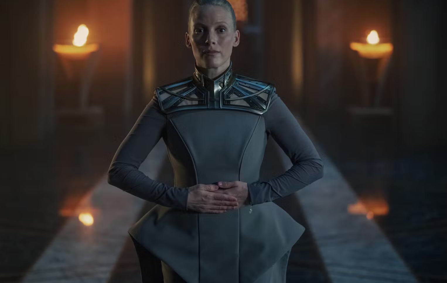 A female sci-fi character in a torch-lit chamber