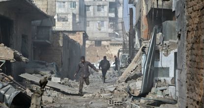 Syrian men run through an alley in the rebel-controlled Mesraba, on the outskirts of Damascus